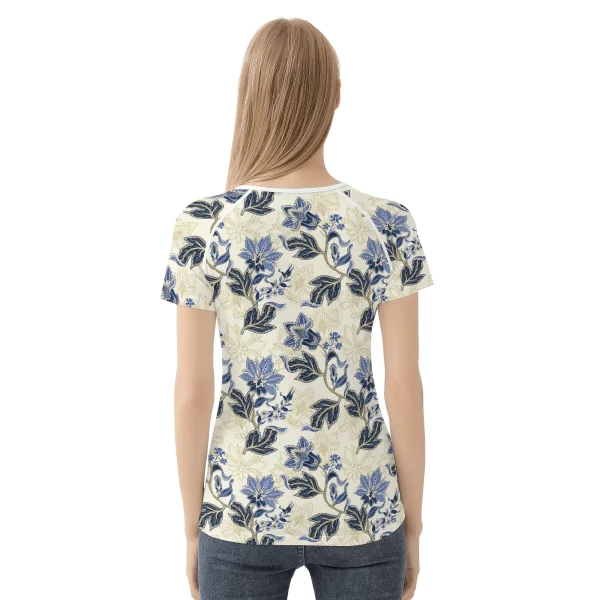 Camiseta de manga corta con estampado floral vintage en azul y dorado sobre fondo crema, mostrando costuras reforzadas y diseño único.