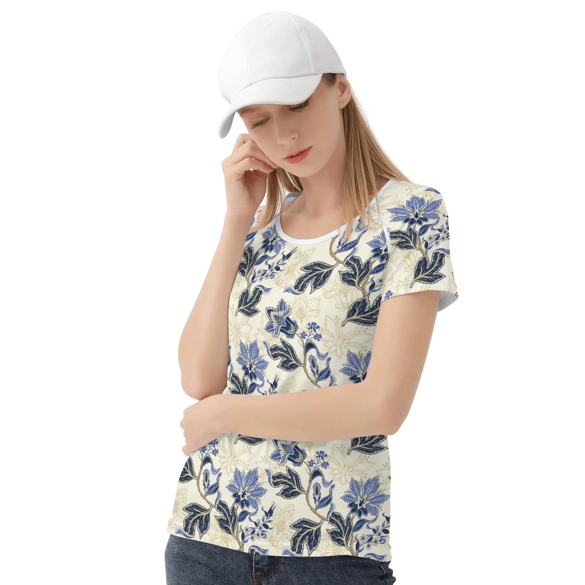 Camiseta de manga corta con estampado floral vintage en azul y dorado sobre fondo crema, mostrando costuras reforzadas y diseño único.