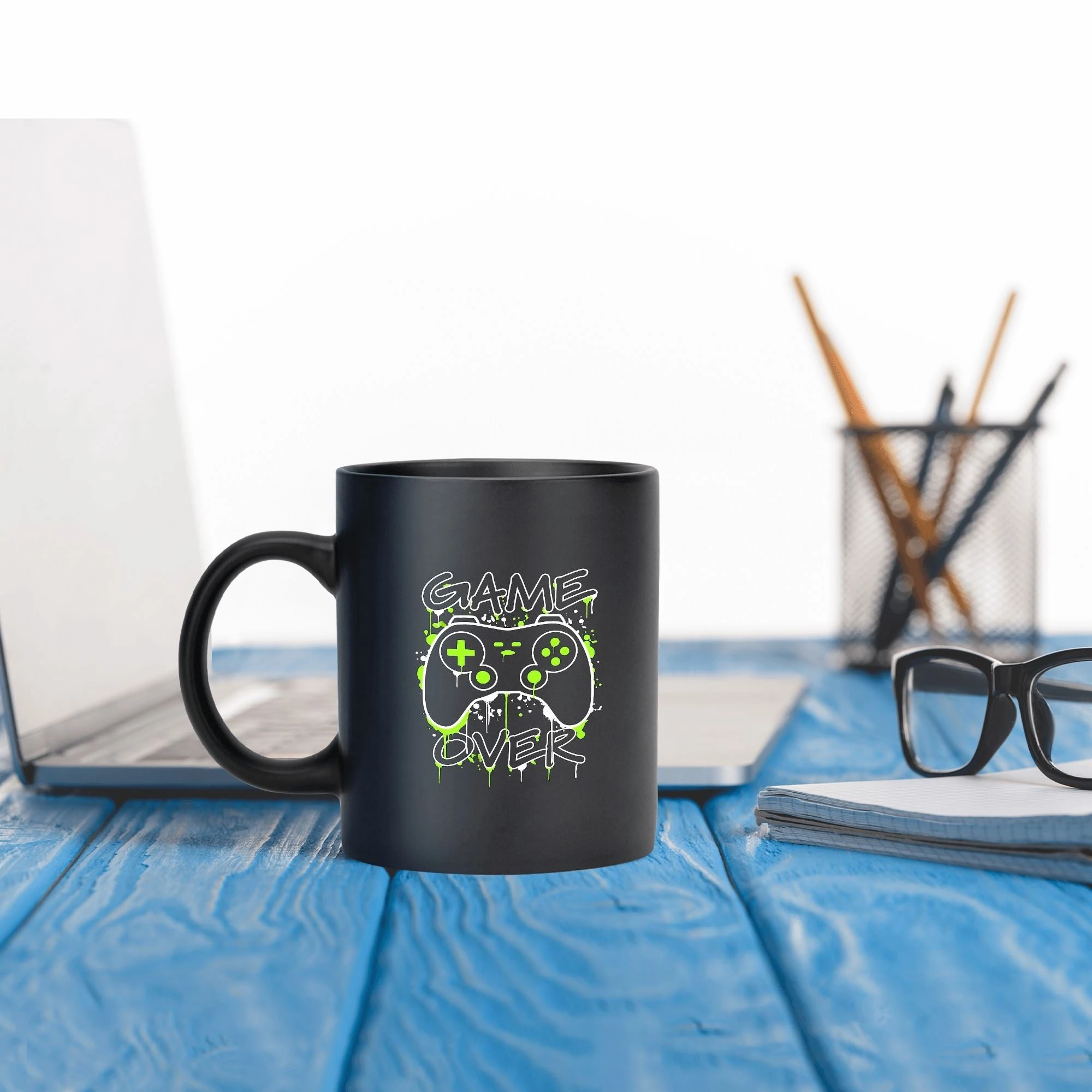 Taza negra de cerámica de 11 oz con estampado de mando de videojuegos en blanco y verde neón, y texto "GAME OVER" con efecto de goteo.