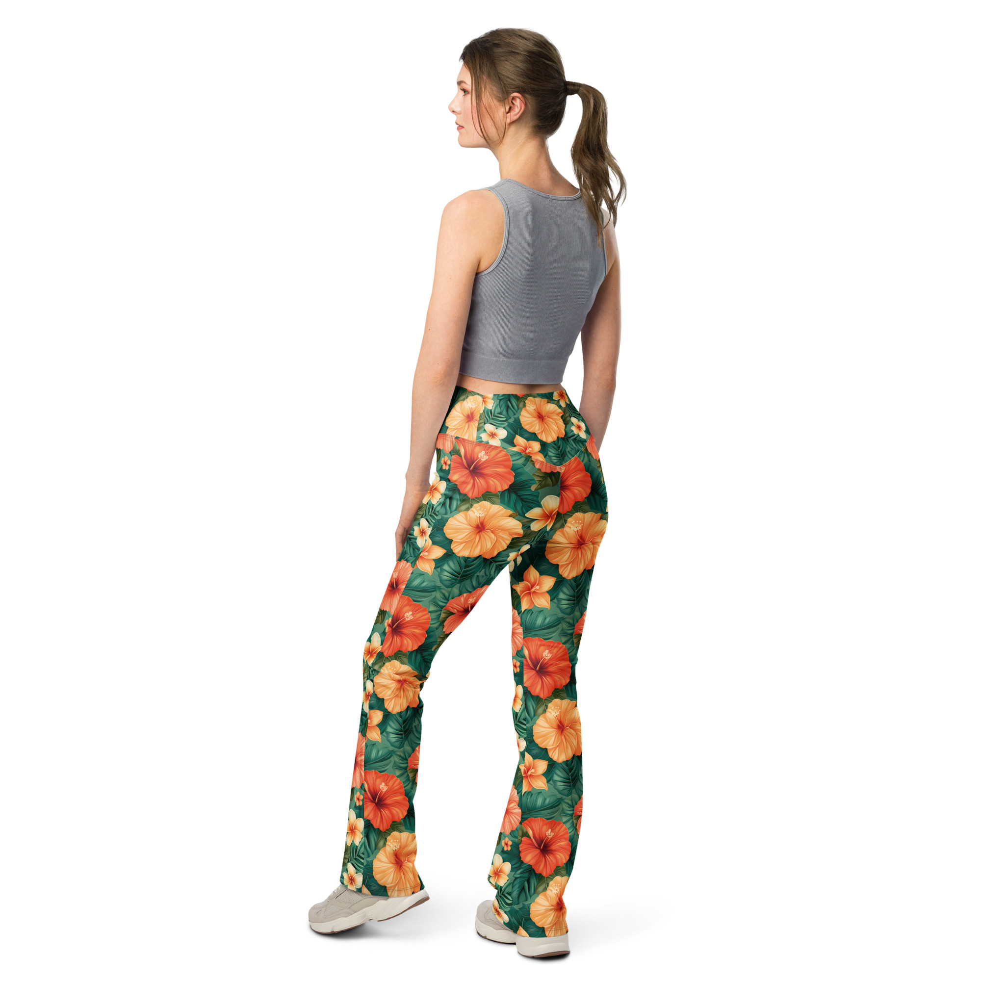 Mujer con leggins acampanados tropicales con flores hibisco rojas, naranjas y amarillas – colección Tropic – Heat.