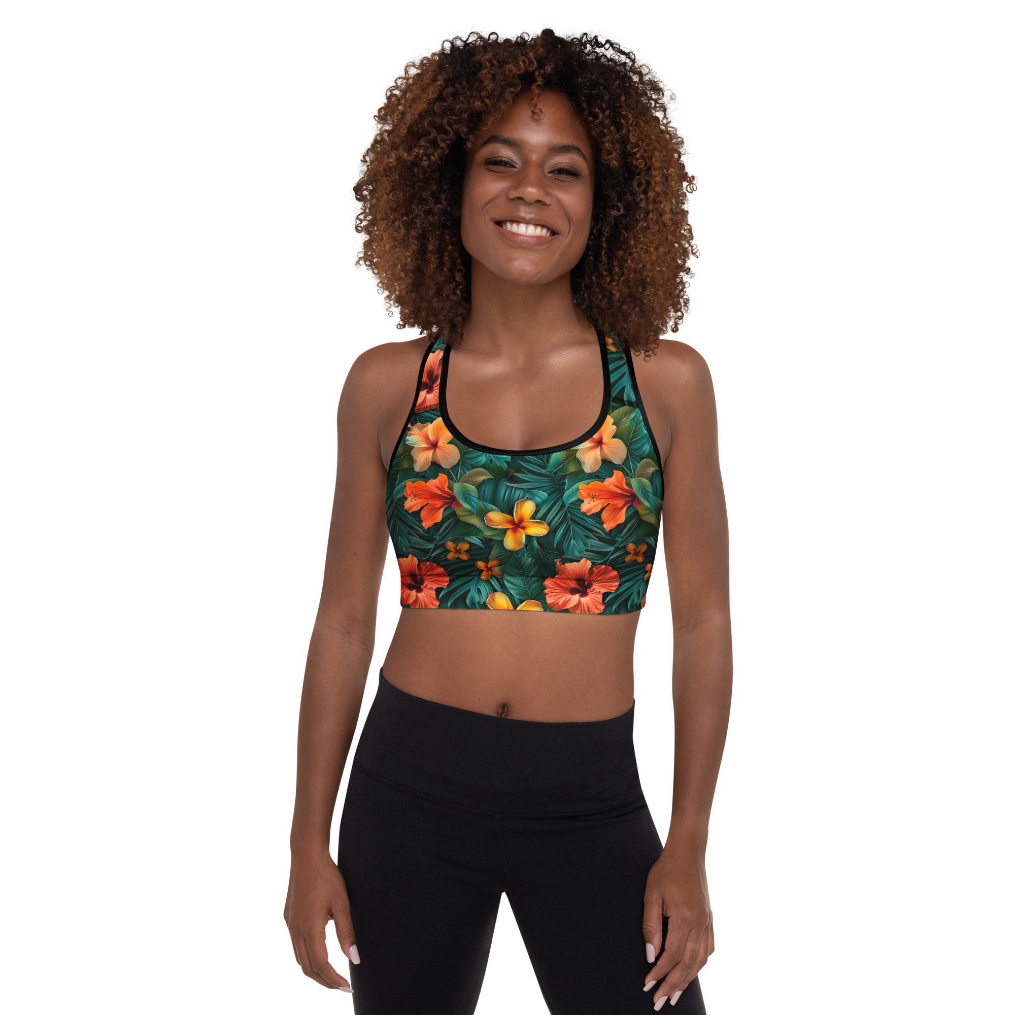 Mujer con sujetador deportivo tropical estampado integral en fondo oscuro, sonriente y en pose fitness