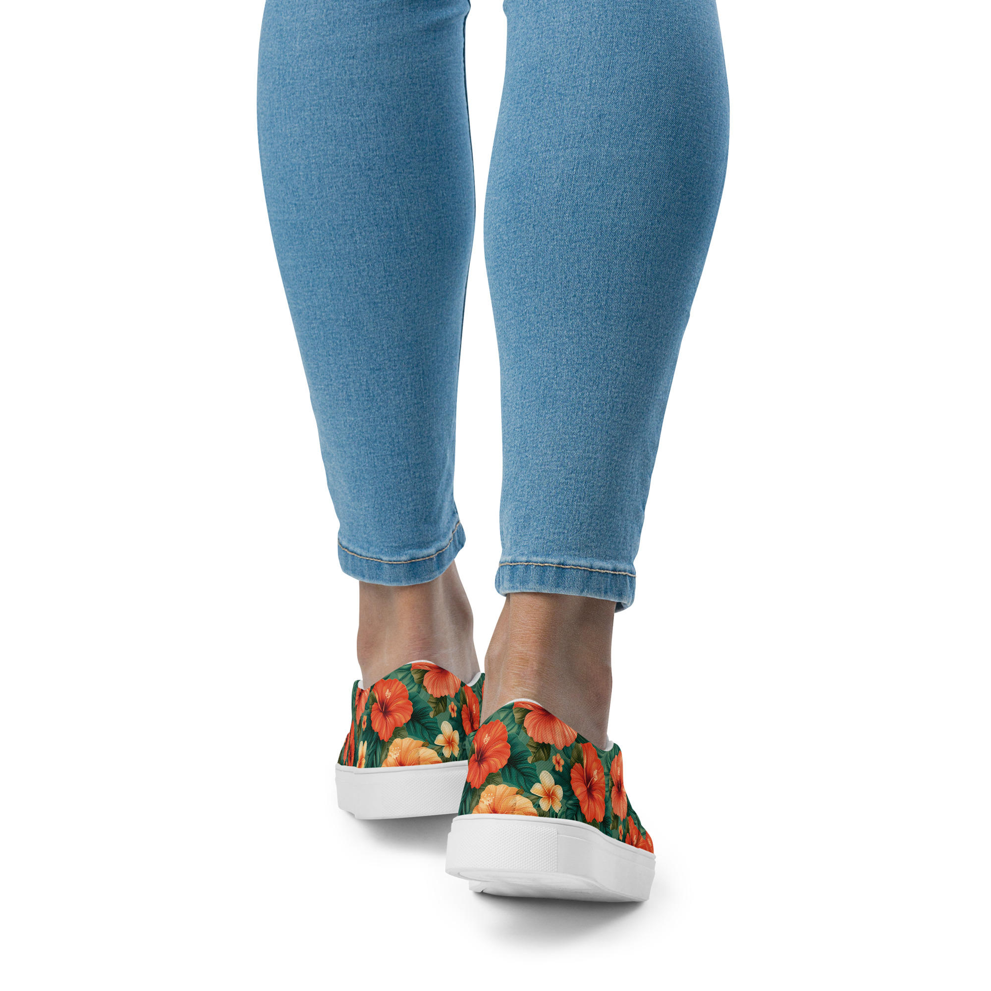 Zapatillas sin cordones con flores hibisco rojas y naranjas sobre fondo verde, combinadas con vaqueros – colección Tropic – Heat.