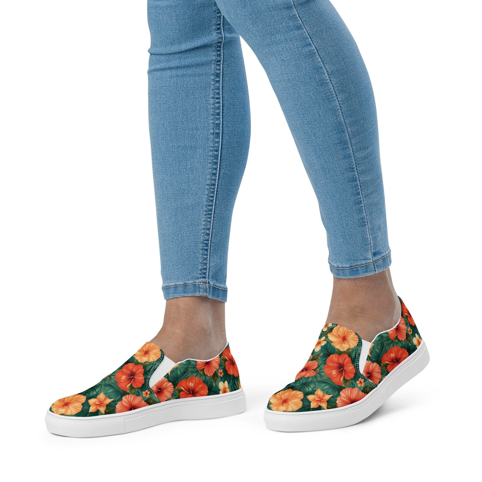Zapatillas sin cordones con flores hibisco rojas y naranjas sobre fondo verde, combinadas con vaqueros – colección Tropic – Heat.