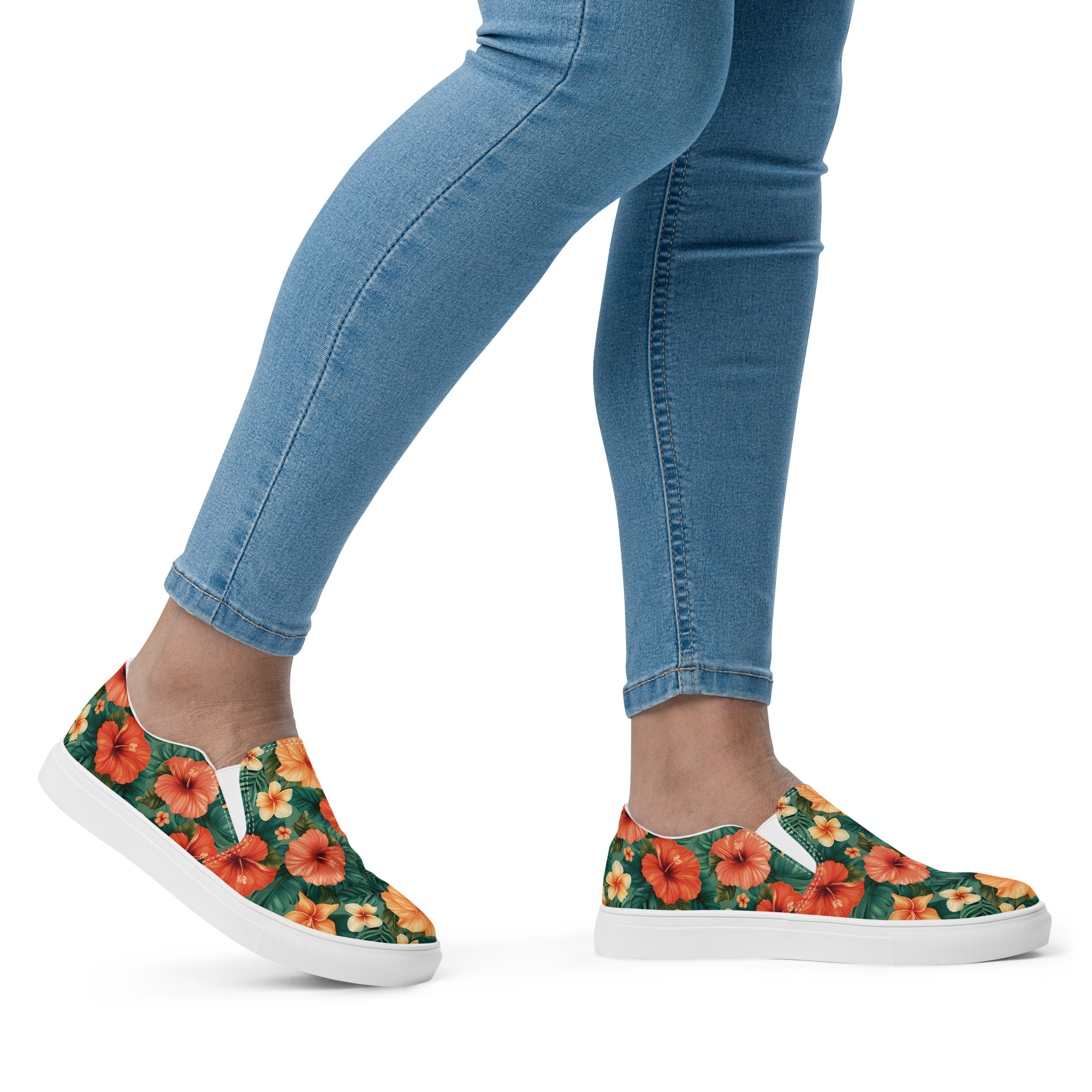 Zapatillas sin cordones con flores hibisco rojas y naranjas sobre fondo verde, combinadas con vaqueros – colección Tropic – Heat.